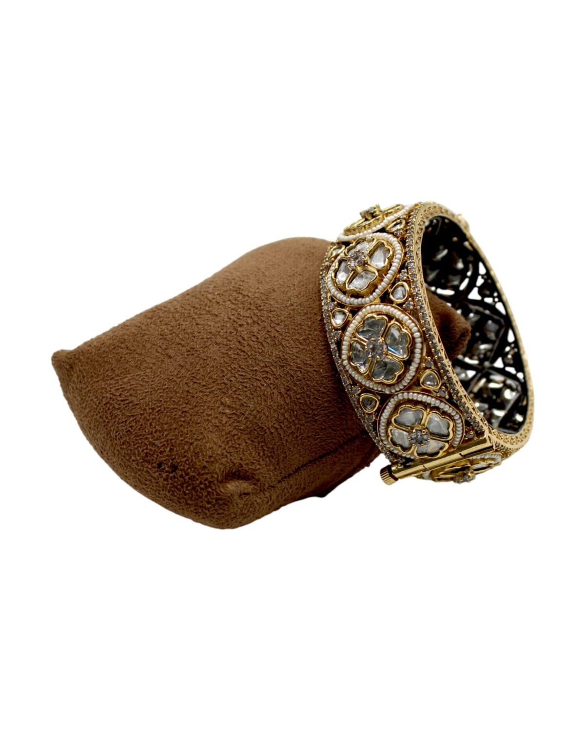 Elegant Gold and Stone-Studded Bracelet Displayed on a Soft Cushion