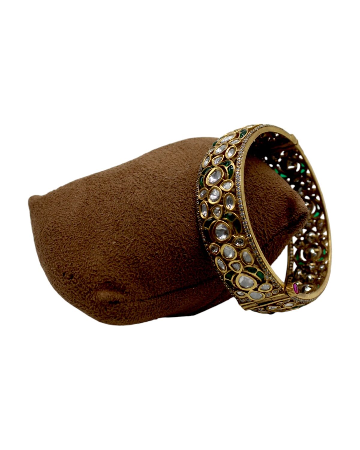 Elegant Gold Bangle with Intricate Stone Inlay on Velvet Cushion